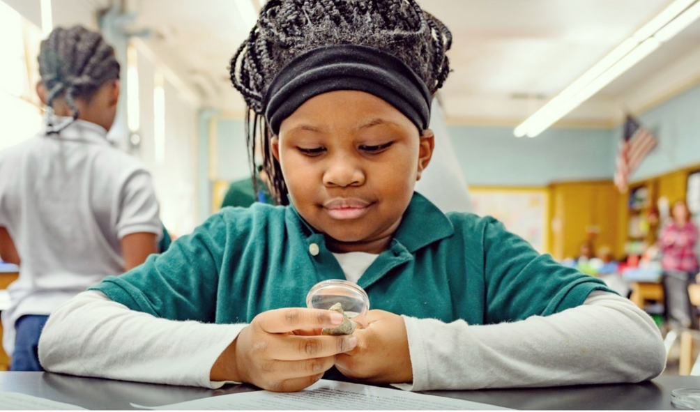 African American female student looking thru magnifying glass