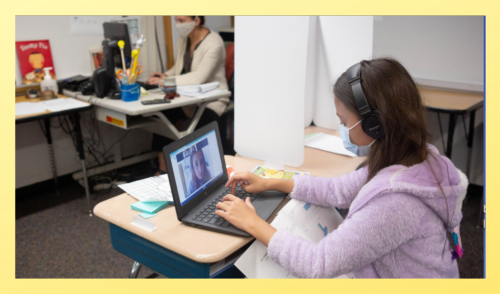 Female student working on laptop at desk with mask on