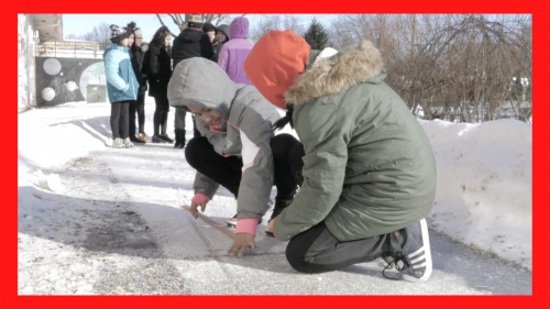 Students outside in winter on looking at something on sidewalk