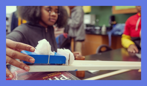 African-American female student doing experiment with toy car on plank
